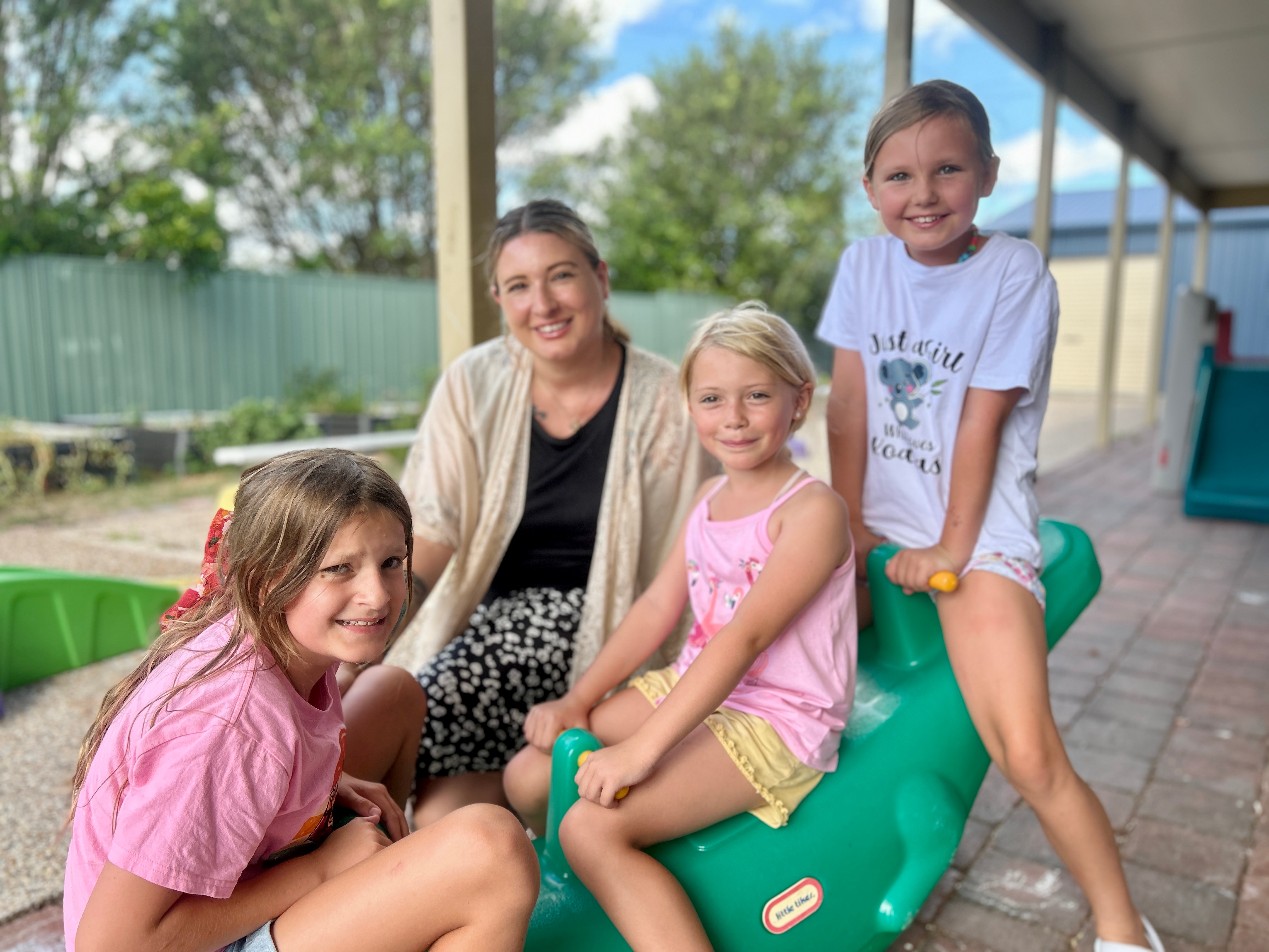 Mãe e filhos em um crocodilo de plástico.