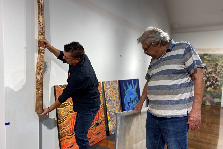 Two men setting up an exhibition 