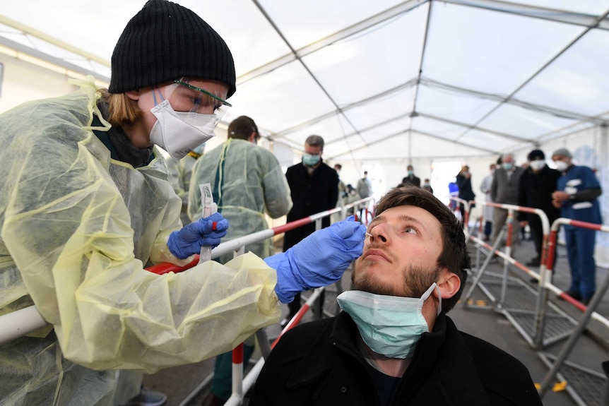 A female health worker sticking a swab up a man's nose