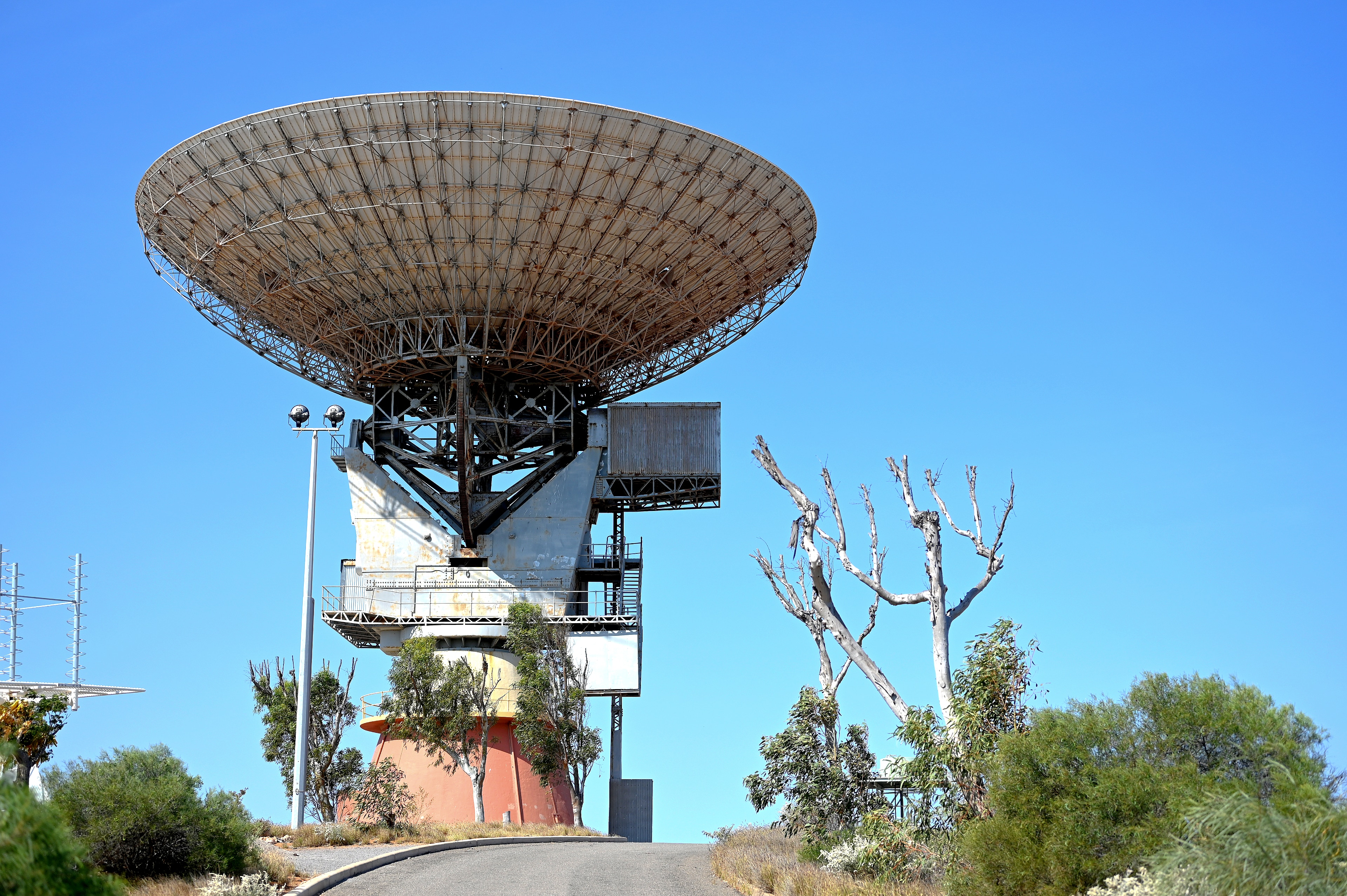 A large ground-based satellite dish pointing straight upwards against a blue sky backcrop