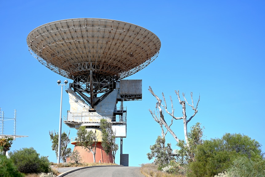 A large ground-based satellite dish pointing straight upwards against a blue sky backcrop
