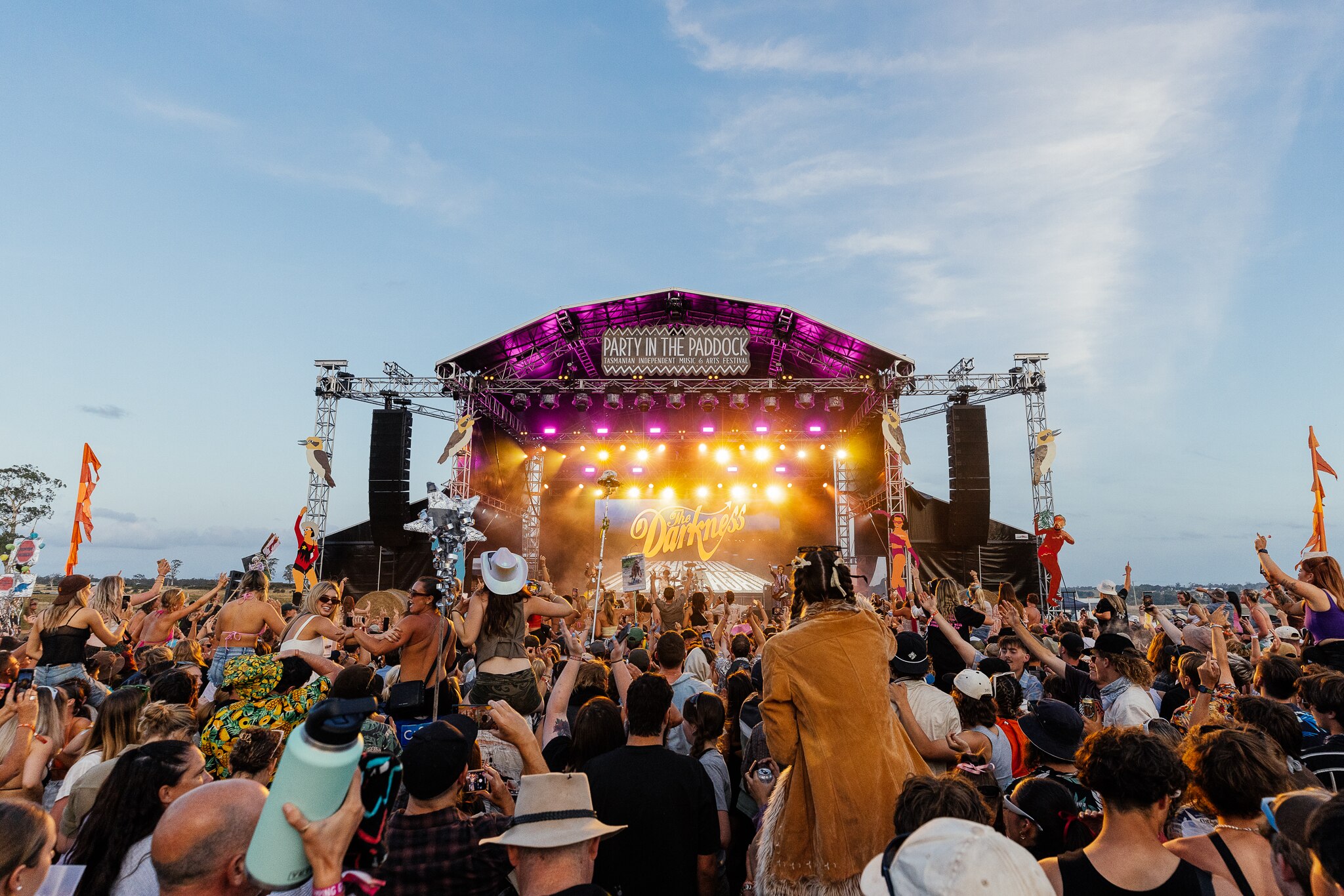 A crowd is in front of a stage at Party In The Paddock on an overcast day