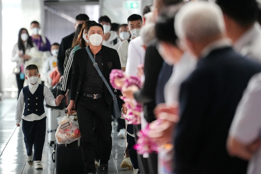 A group of travellers wearing masks arriving in at an airport.