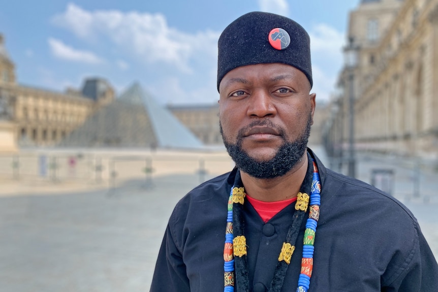 A man with the Louvre pyramid in the background.