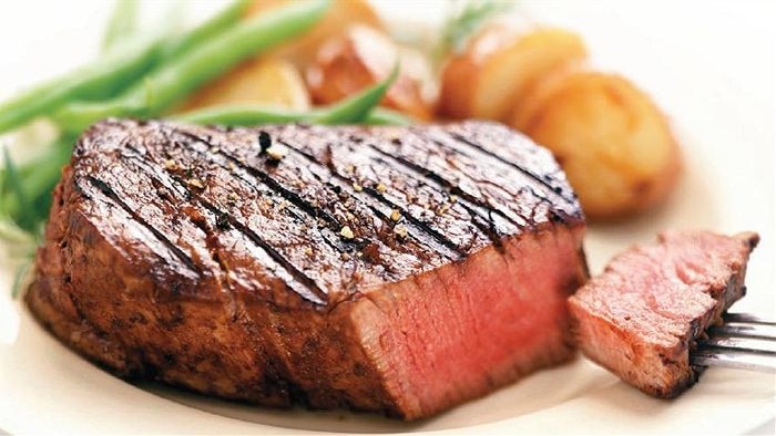 A cooked steak on a plate — cut to show it rare