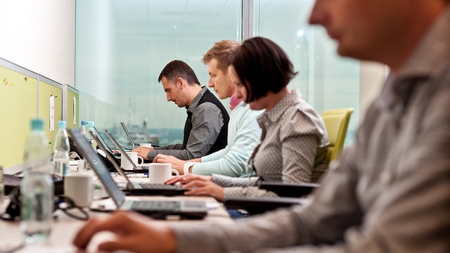 Employees working on laptops in an office.