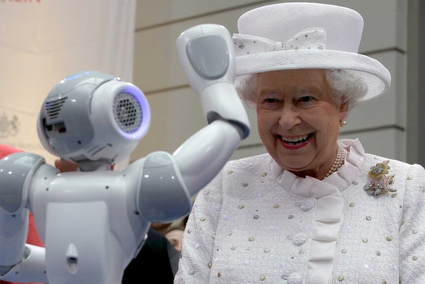 Queen Elizabeth II smiles as a robot waves to her during her visit at the Technical University of Berlin.