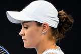 An Australian female tennis player checks the strings on her racquet.
