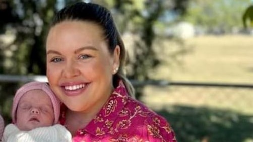 Tayla Cox wears pink and holds her baby girl Murphy