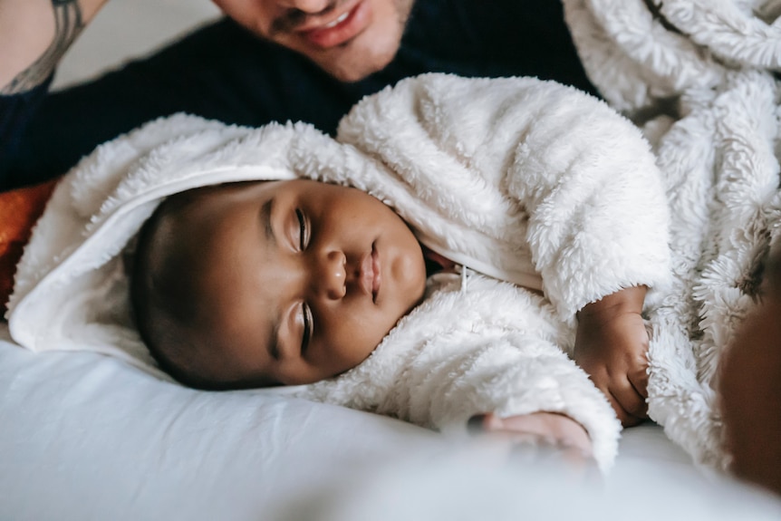 A baby sleeping in a fluffy white jumpsuit.