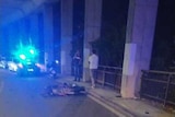 A scooter lays on a street at nighttime with a police car nearby