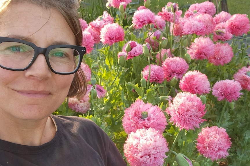 Kate DIxon stands in front of pink poppies