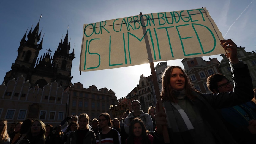 a girl holds a sign during a climate change protest in Prague