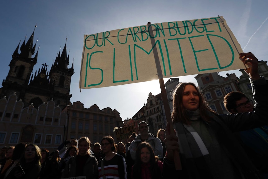 a girl holds a sign during a climate change protest in Prague