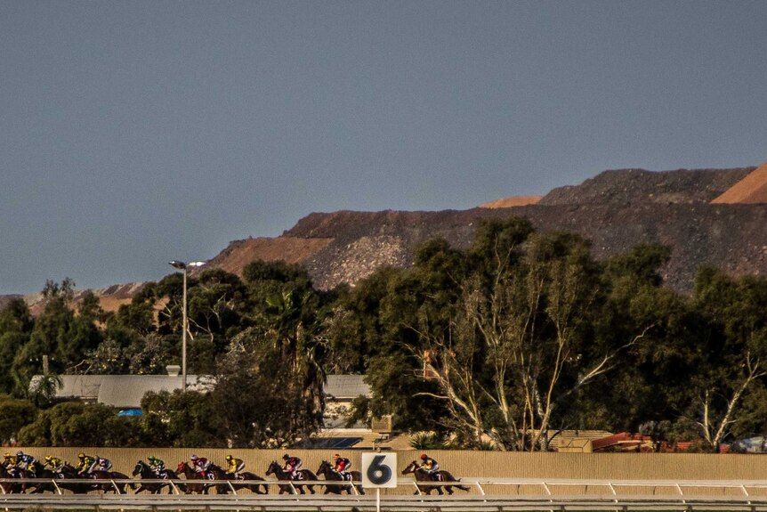 Horses round the bend at the Kalgoorlie-Boulder Racing Club, with the Super Pit gold mine visible in the background.
