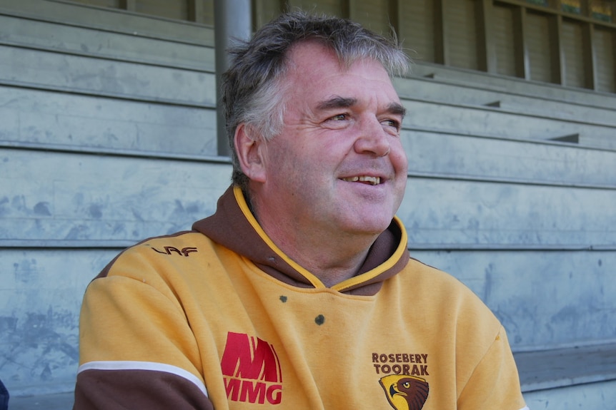 A football coach sitting in the grandstand. 