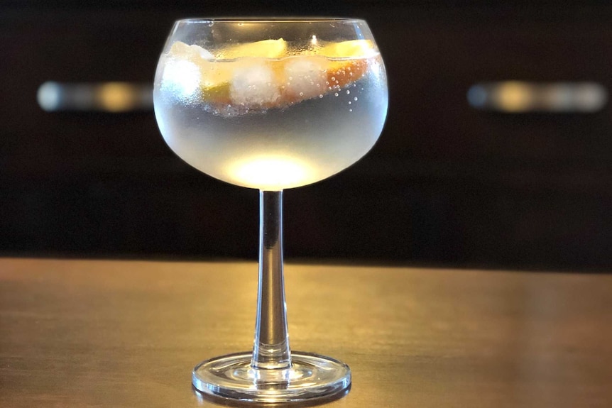 Gin in a glass sits on a bar.