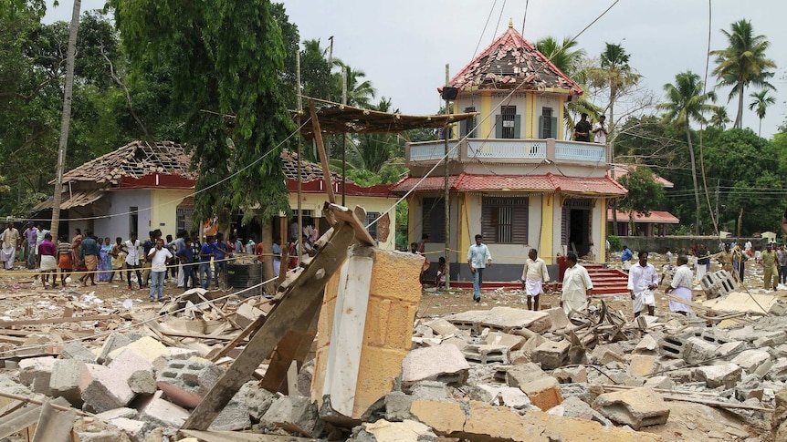 People stand next to debris after a broke out at a temple
