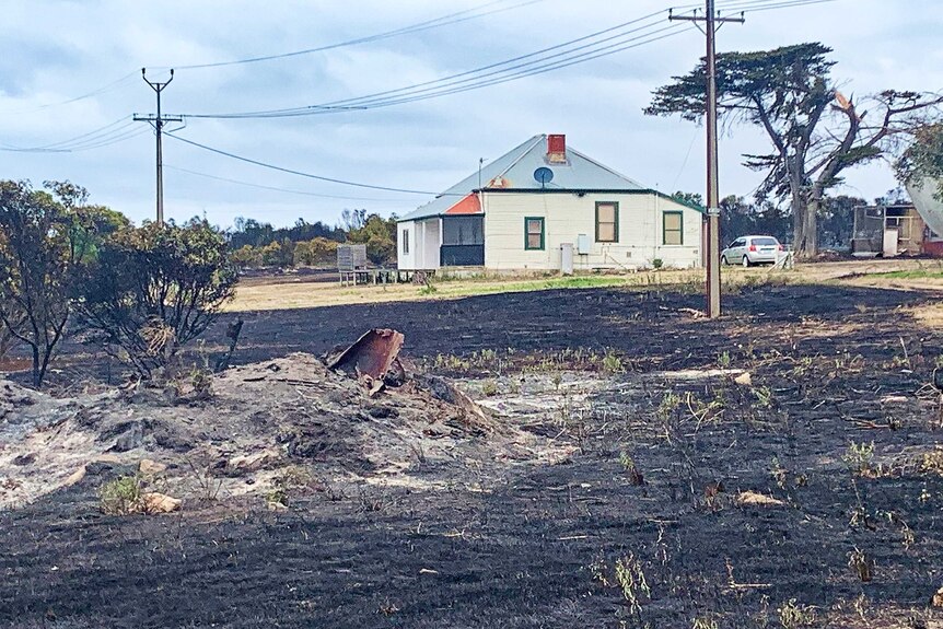 scorched ground in front of an undamaged house