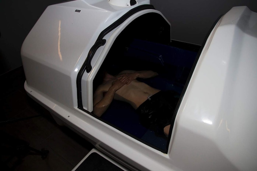 A man lies in darkness in an open sensory deprivation tank at a facility in Canberra.