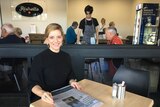 Woman sitting at cafe table with newspaper