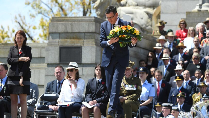 a man walks down steps at a memorial to lay a wreath of flowers
