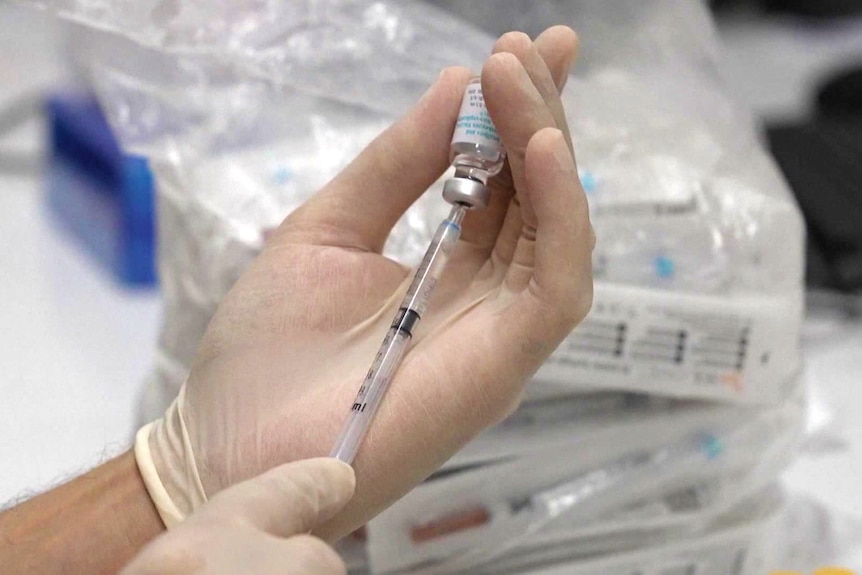 a person holding a vaccines and vial of dose