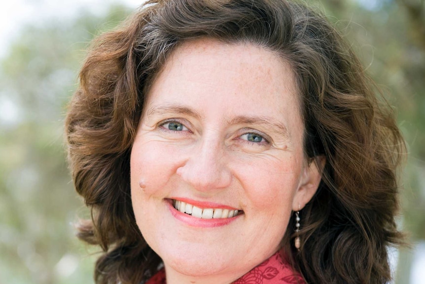 A smiling woman with a red shirt, smiling.