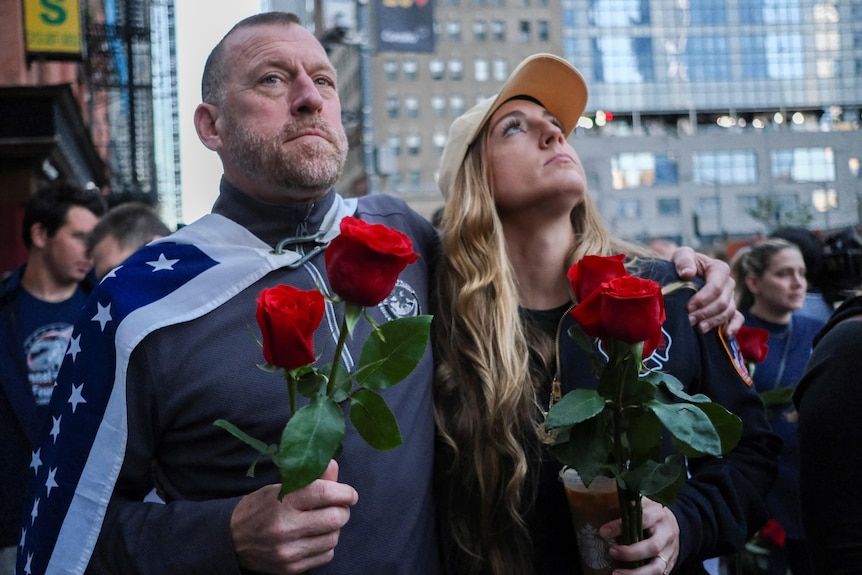 A man and woman looking upward while holding a red rose.