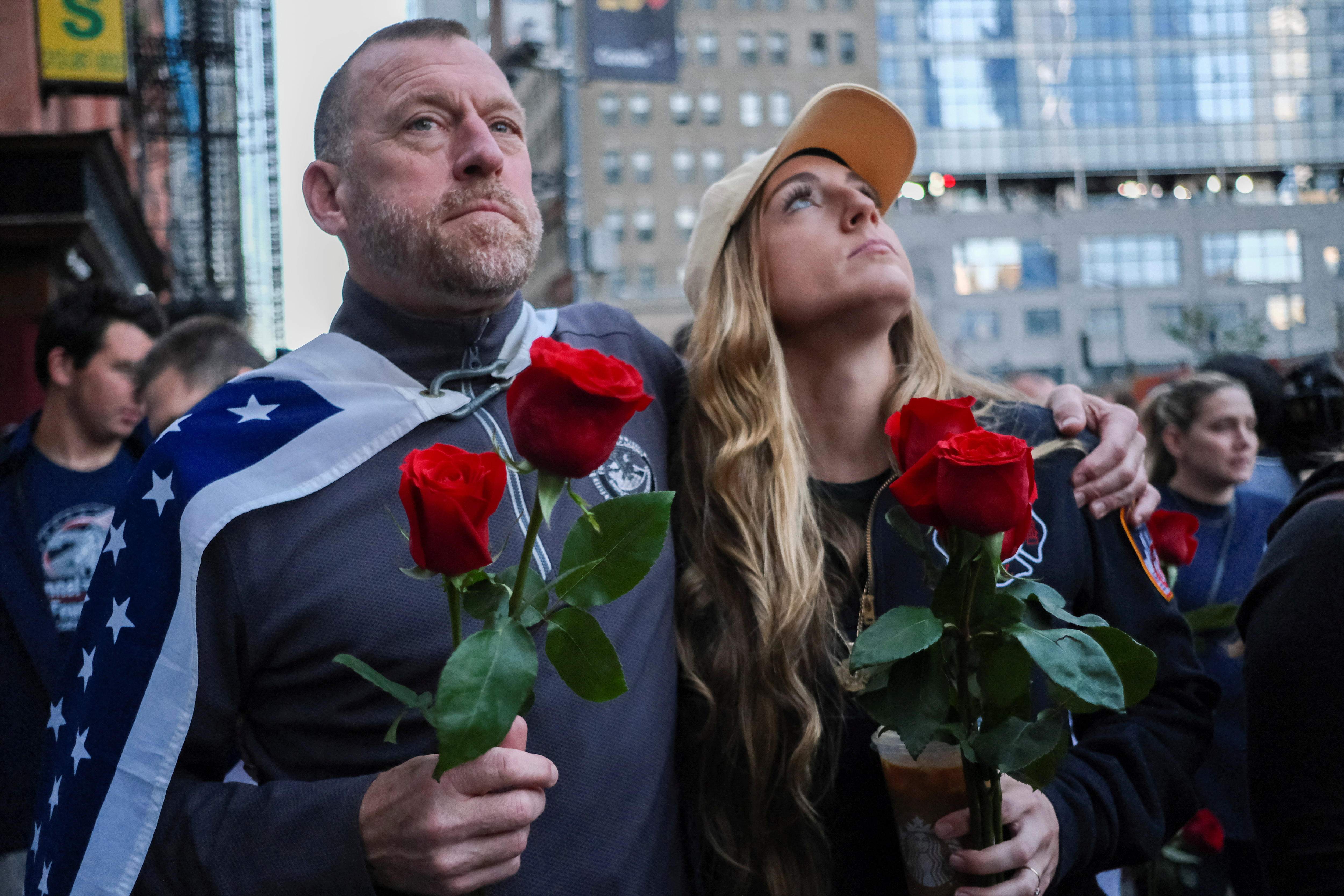 一男一女手持一朵红玫瑰向上看。