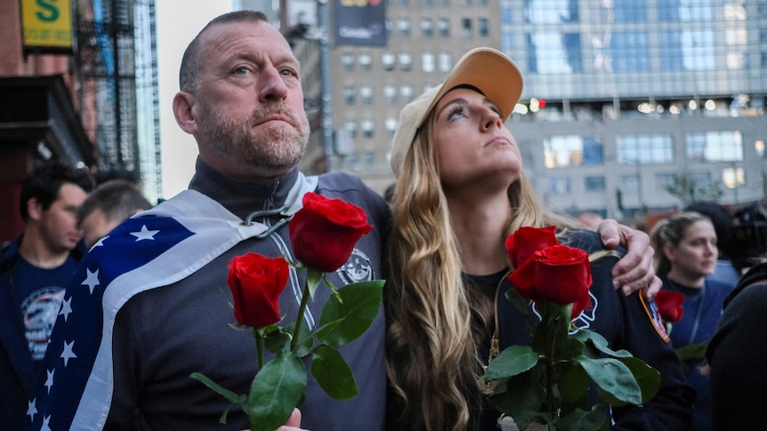 A man and woman looking upward while holding a red rose.