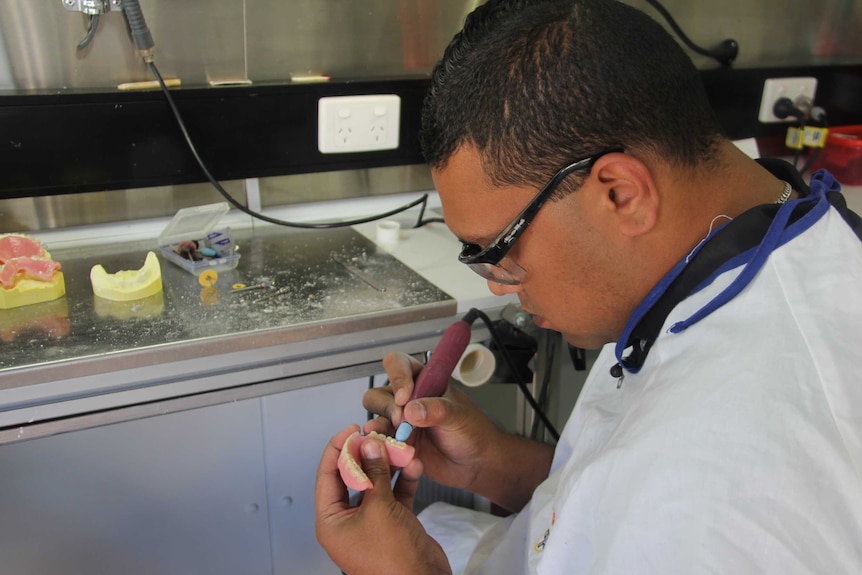 Paul Talbot works on a set of dentures.