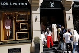 People line up outside a Louis Vuitton shop.