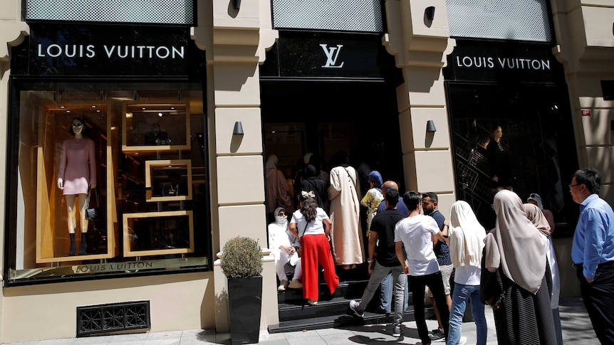 People line up outside a Louis Vuitton shop.