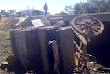 A horse-drawn stagecoach lies on its side after crashing off a bridge on the outskirts of Longreach.