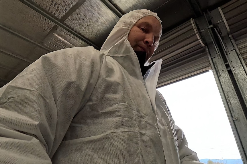 Farmer wearing protective suit standing in a shed.