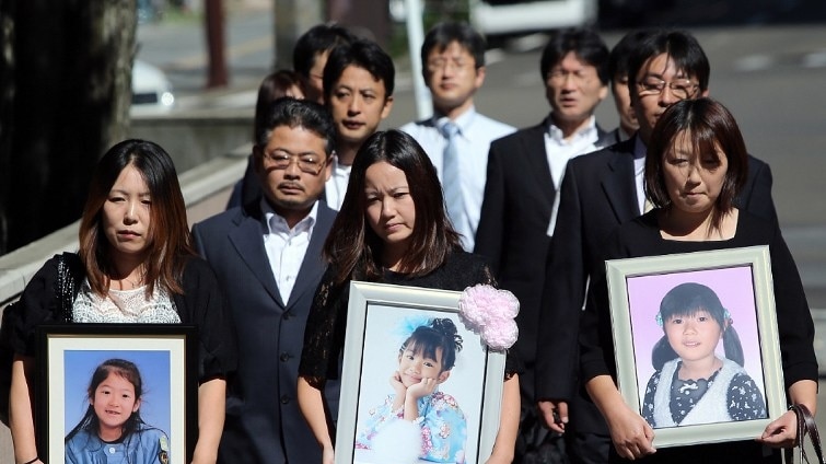 The families of kindergarten children who died on a bus in the 2011 tsunami walk near the court.