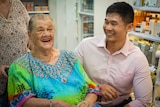 A young pharmacist laughs with an older lady customer.