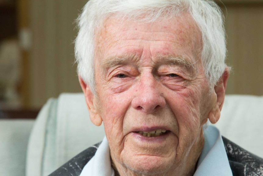 An elderly man looks at the camera.