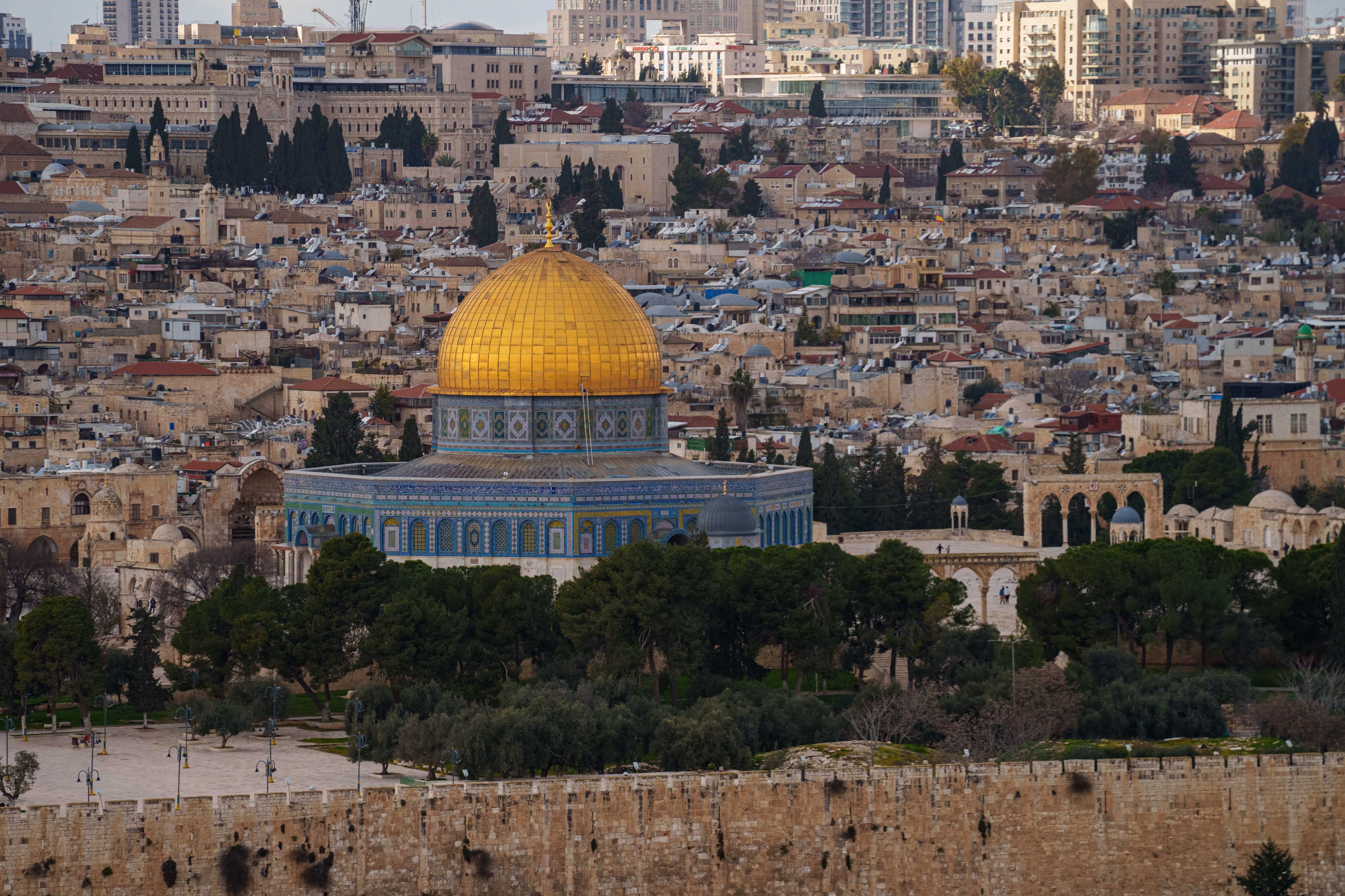 The golden roof of the Dome of the Rock shines against the begie sprawl of buildings.