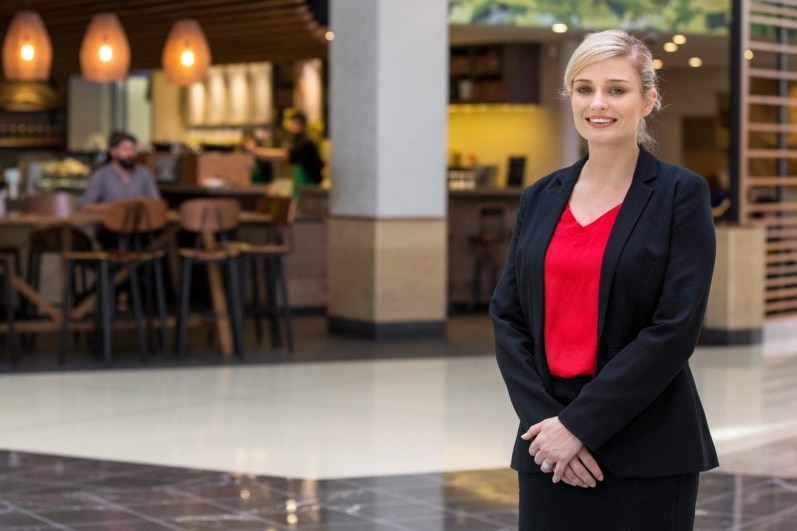 A woman smiling standing outside a cafe