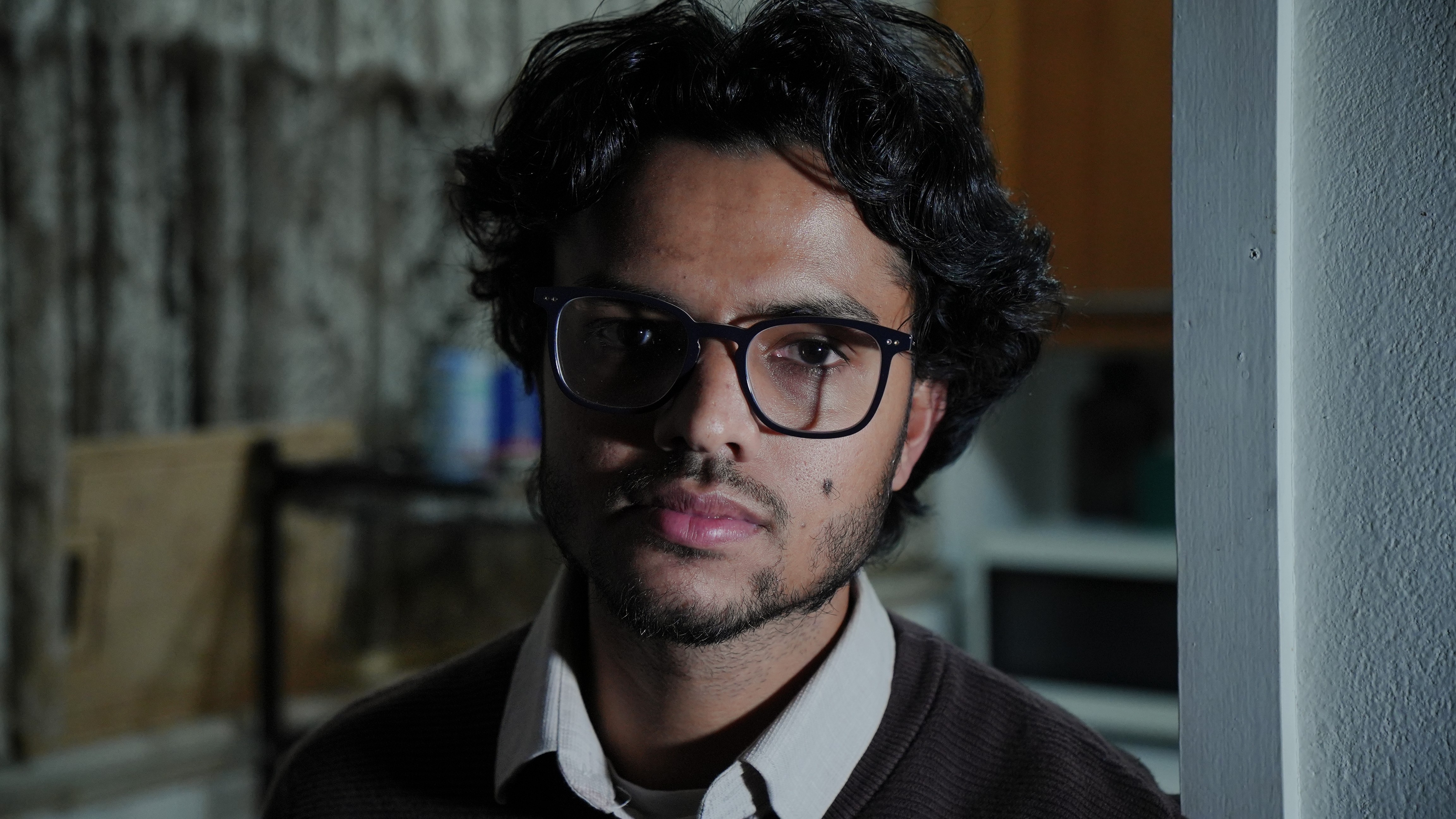 A man with dark hair and glasses looking into the camera.