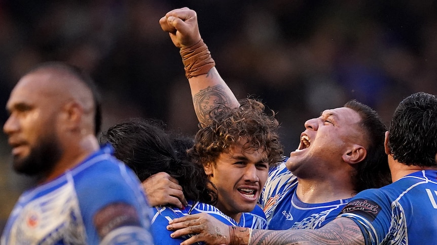 Josh Papali'i raises a fist as he hugs teammate Chanel Harris-Tavita as Samoa beats Tonga at the Rugby League World Cup.