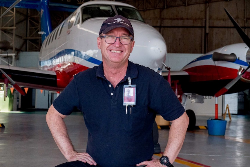 A man kneels in front of an RFDS plane.