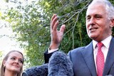 Low down view of Malcolm Turnbull speaking at a microphone as Fiona Scott looks on.