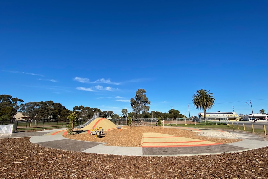 A playground with a riding track and bark in the foreground