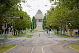 A person crosses an empty street on the first day of a five-day COVID-19 lockdown in Melbourne