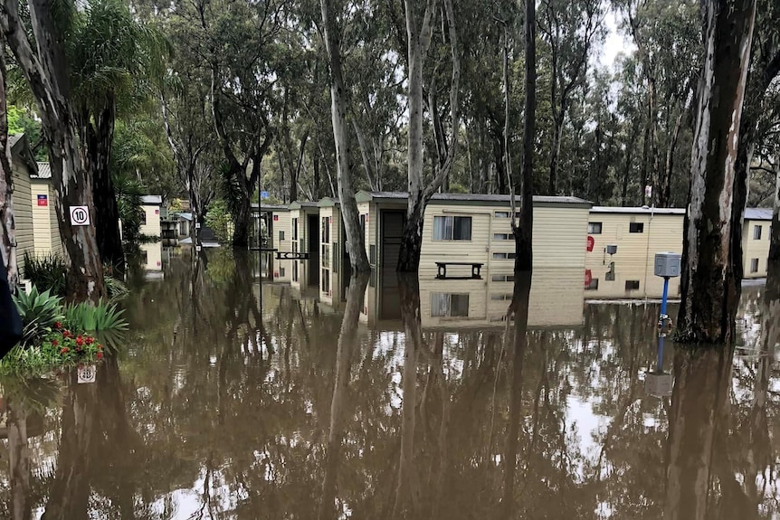 Multiple caravans appear inundated by river water.