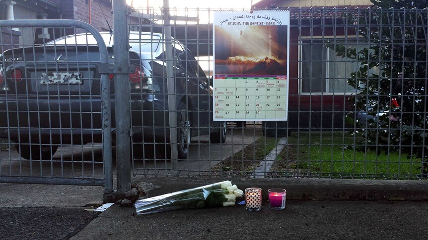 Flowers lay alongside two burning candles outside the home of the parents of Andrew Chan