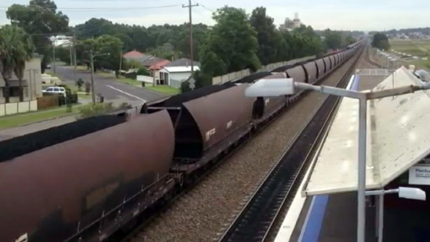 Loaded coal train passes suburban station